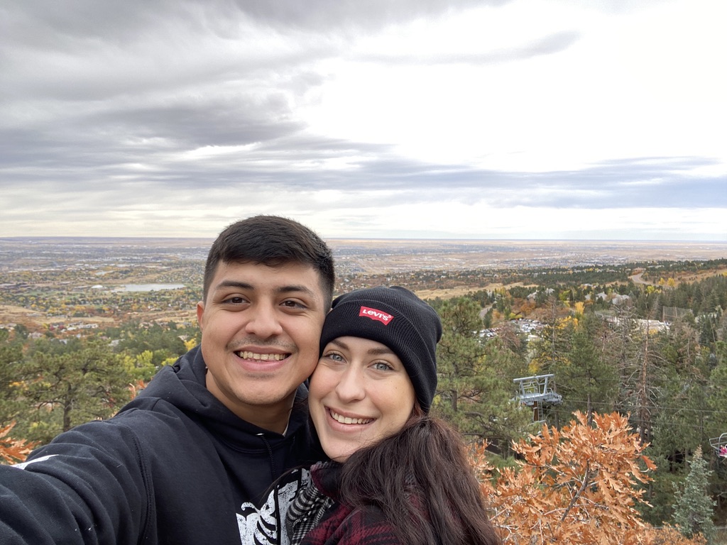 Isaac and Hope smiling together at an overlook surrounded by autumn trees.