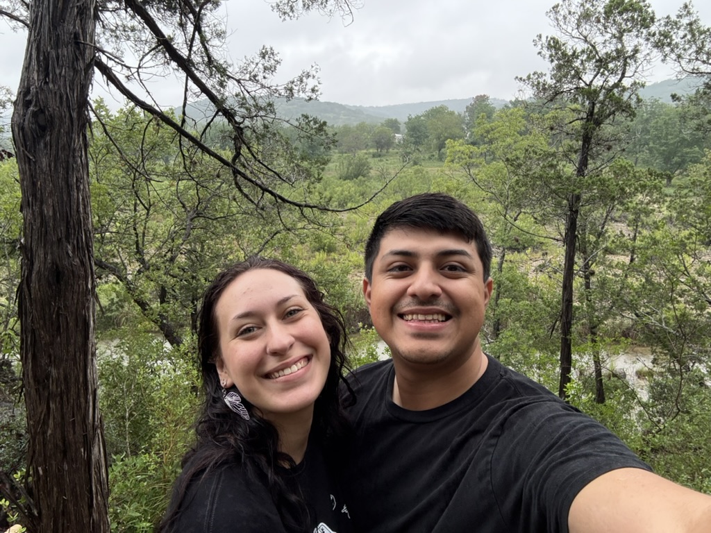 Hope and Isaac smiling together on a wooded trail.